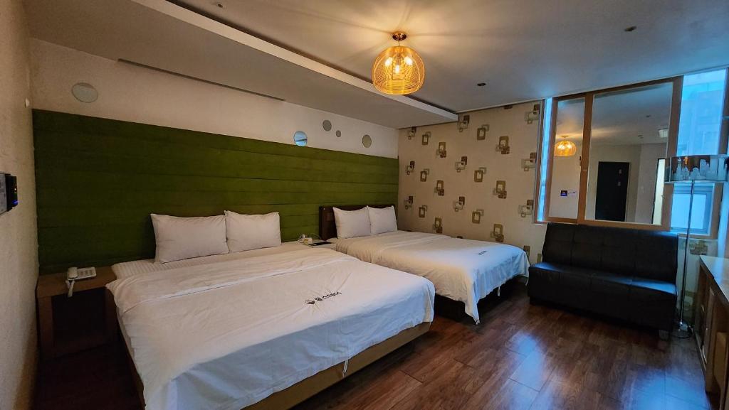 金海市Gimhae Business Hotel K的酒店客房,设有两张床和一张沙发