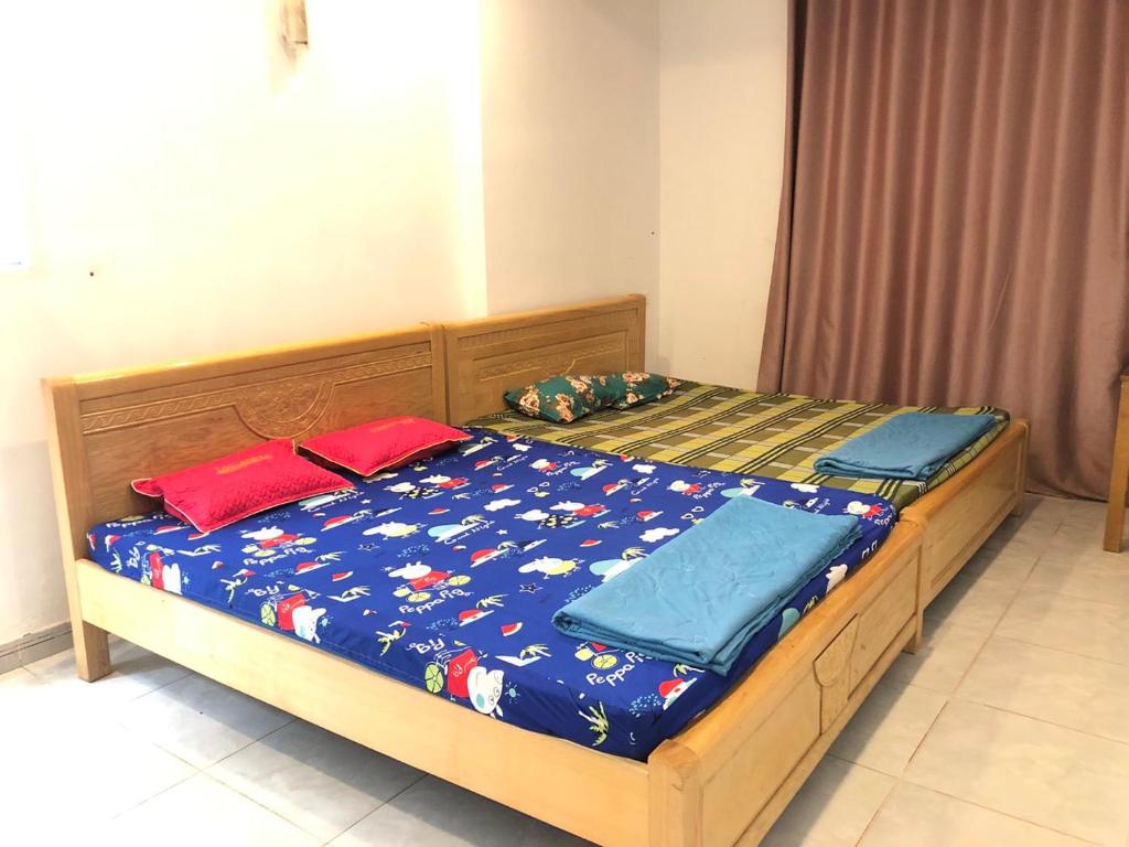 Chơn ThànhNhà Nghỉ Minh Thảo的一张带蓝色棉被和红色枕头的床