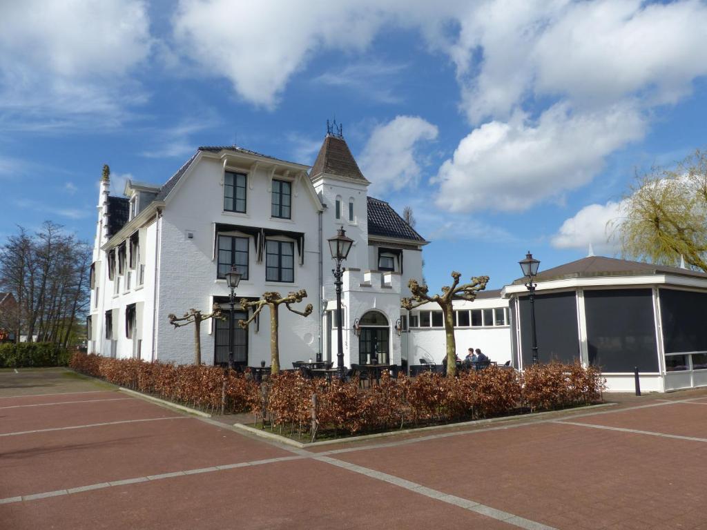 滨海卡特韦克赫伯格·维尔格勒根酒店的一座白色的房子,前面设有一个网球场
