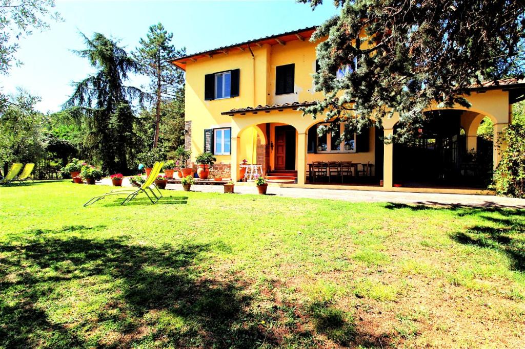 菲利内瓦尔达诺Podere delle Arti的黄色的房子,带两把草坪椅的院子