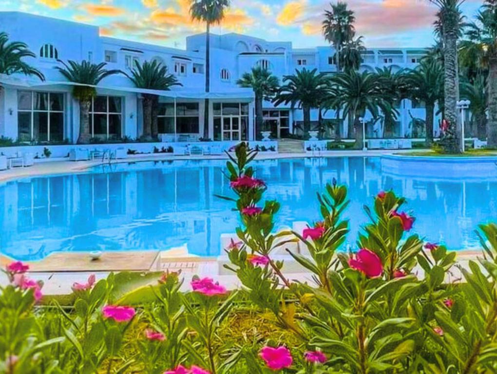 哈马马特Hammamet Serail的一个带粉红色花卉大型游泳池的度假酒店