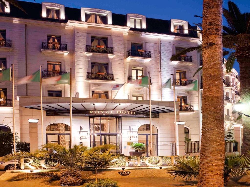奥兰Royal Hotel Oran - MGallery Hotel Collection的前面有旗帜的酒店大楼