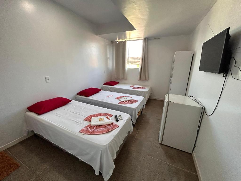 帕劳阿佩巴斯Dantas Hotel的客房设有三张床和一台平面电视。