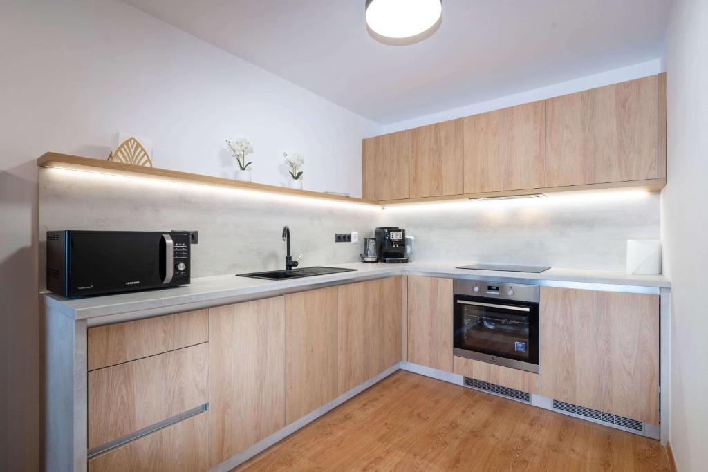 多纳瓦利Apartmanica Residence 511的厨房配有木制橱柜、微波炉和水槽。