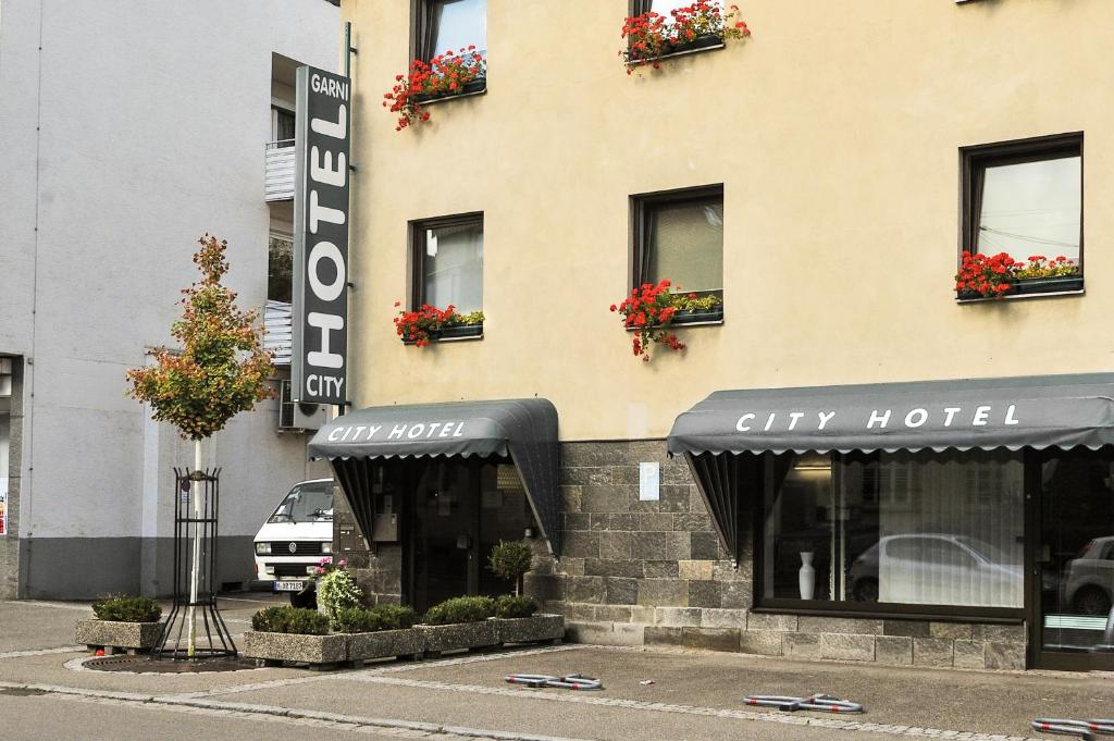 费尔巴赫City Hotel Fellbach 24H CHECK-IN的城市酒店建筑,窗户上有鲜花