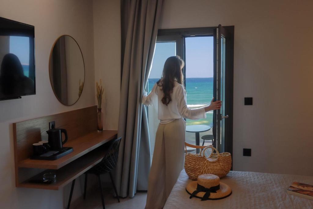 阿默达拉-伊拉克利翁Tropical Beach A的站在酒店房间,望向窗外的女人