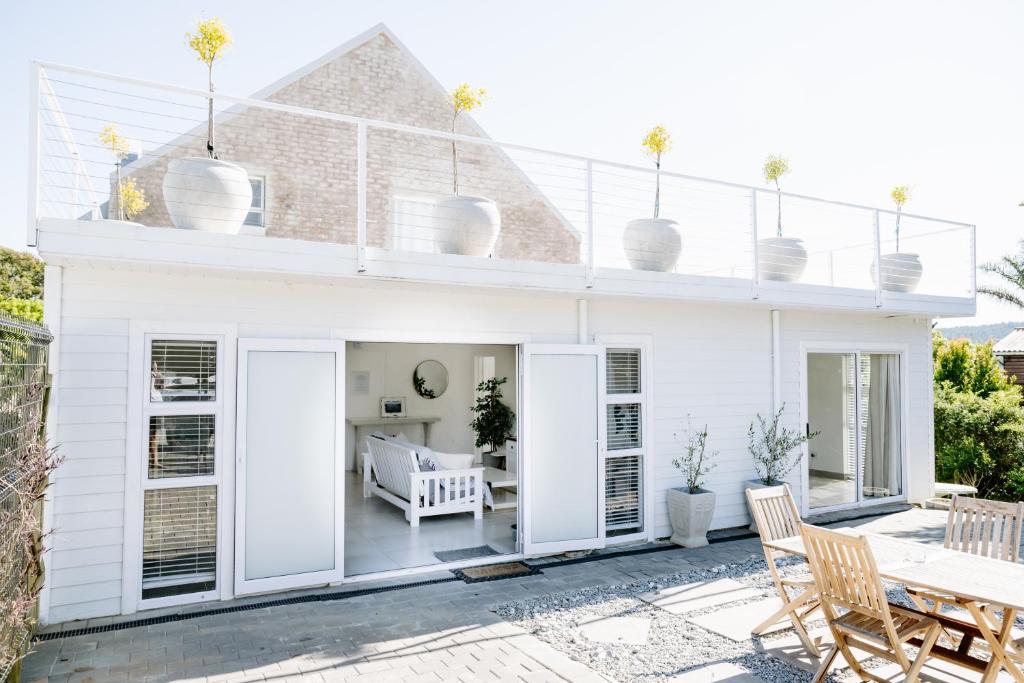 赫罗德斯湾Huis Marais的白色的房子,设有配有桌椅的庭院