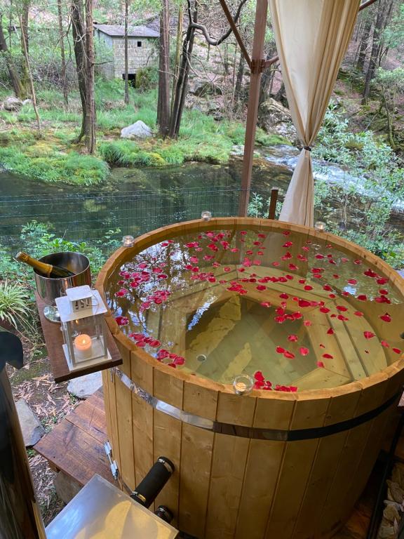 维亚纳堡Wild Glamping Portugal with hot tub to relax in Viana do Castelo的河前满布鲜花的木桶