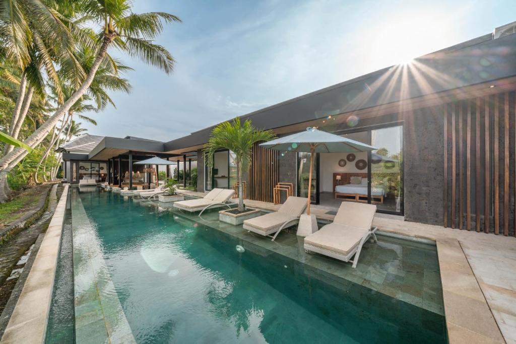 乌布Villa Surga - 4BR Heavenly Ricefields View Villa in Ubud的一个带躺椅的游泳池以及一座房子