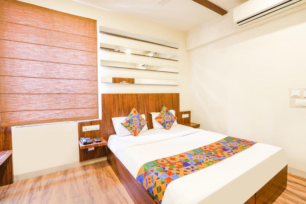 海得拉巴FabHotel Arastu的卧室配有一张带彩色枕头的大型白色床。