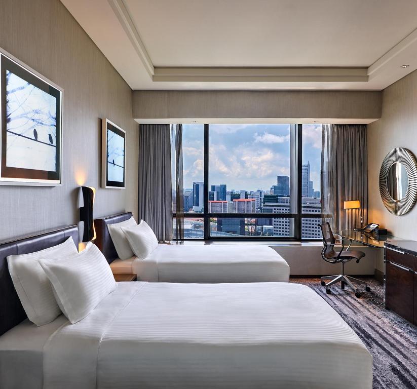 新加坡Carlton City Hotel Singapore的酒店客房设有三张床和窗户。