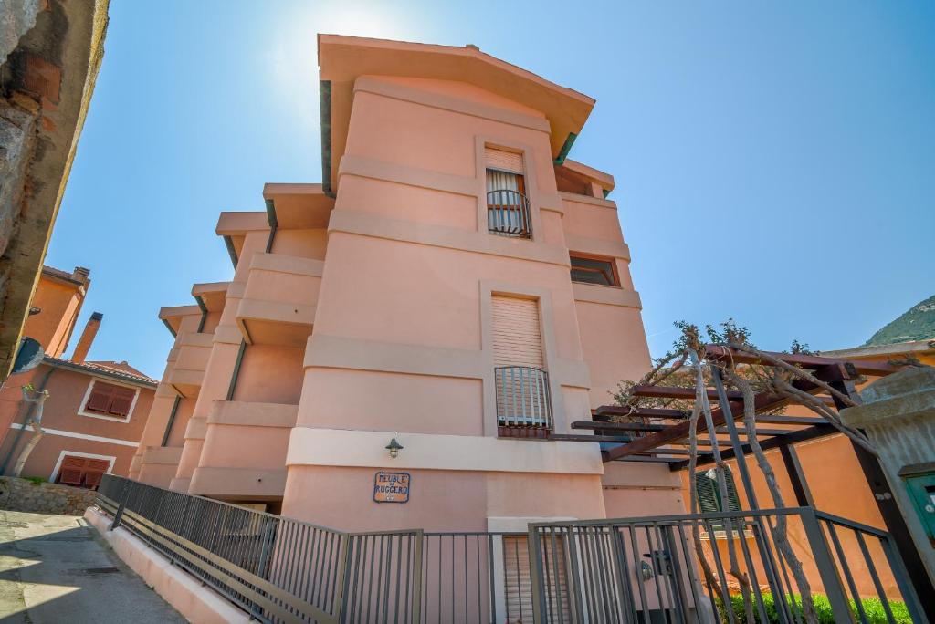 吉廖港Hotel Da Ruggero的粉红色的建筑,前面有栅栏