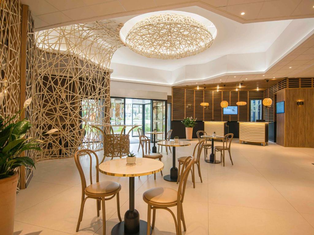 尼斯诺富特尼斯阿里纳斯阿罗伯特酒店的一间带桌椅和吊灯的餐厅