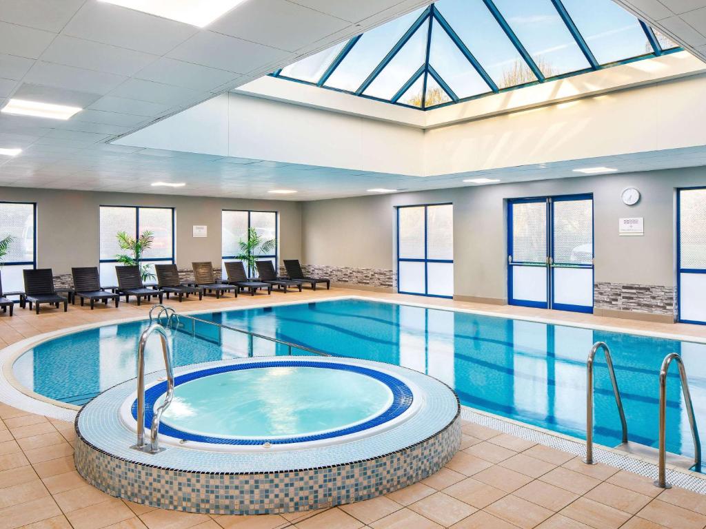 西布罗姆维奇Mercure Birmingham West Hotel的一座大型游泳池,在酒店的房间内配有热水浴缸