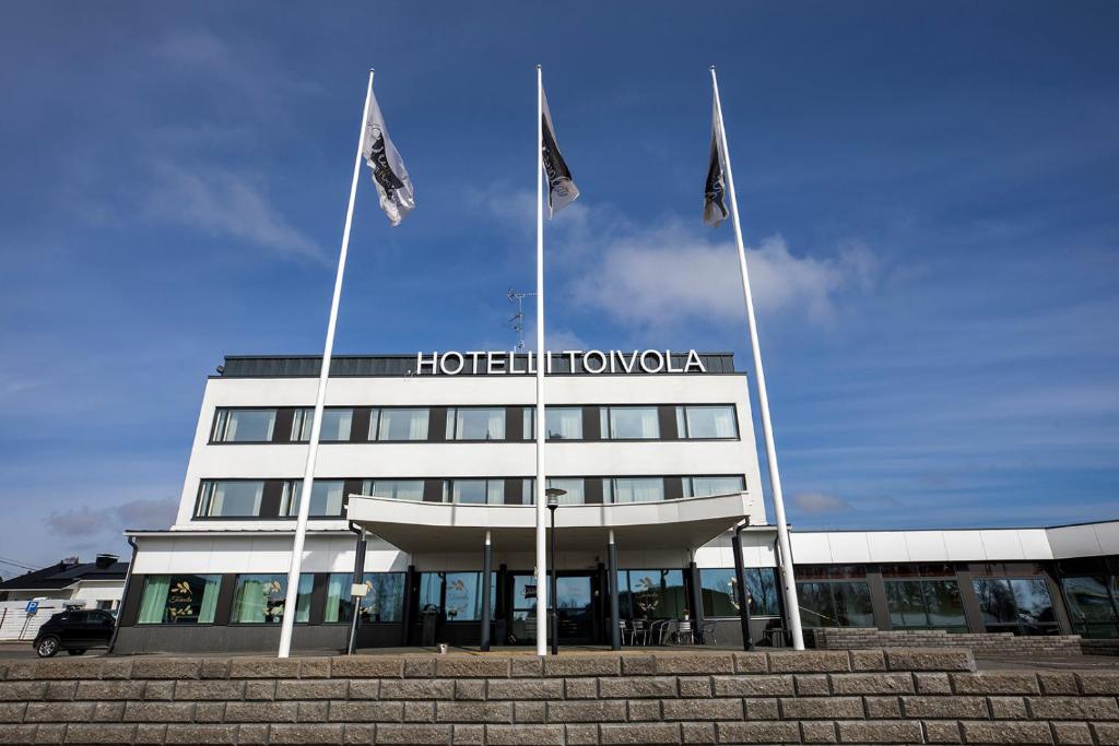 凯米Hotelli Toivola的大楼前有三面旗帜的酒店