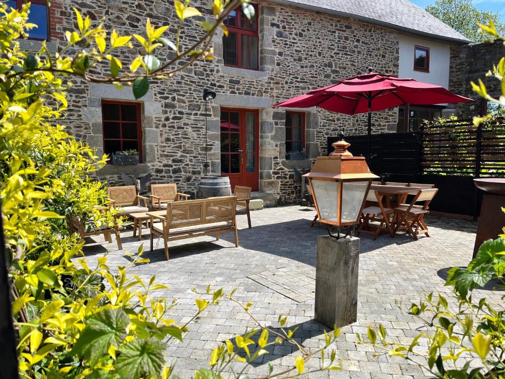 多尔德布列塔尼Domaine du tertre ychot的一个带桌子和红色遮阳伞的庭院