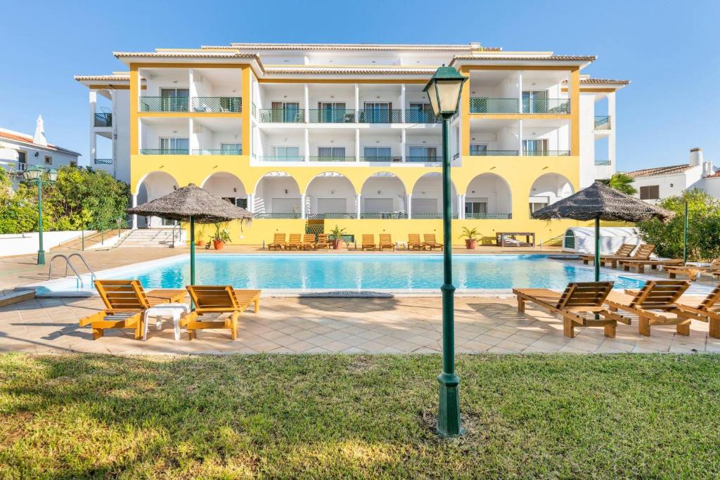 阿尔图拉Apartamentos Turisticos Alagoa Praia的酒店设有带椅子和遮阳伞的游泳池