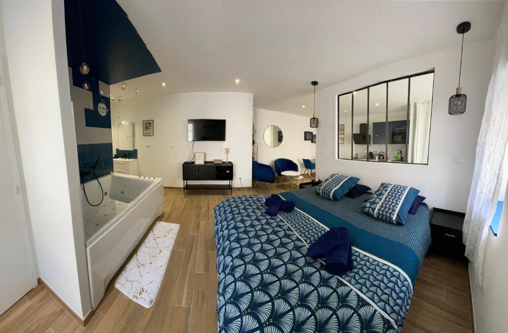 Cosy Appart’ & spa - Appartement privatif - baignoire balnéothérapie的一间卧室配有蓝色的床和浴缸