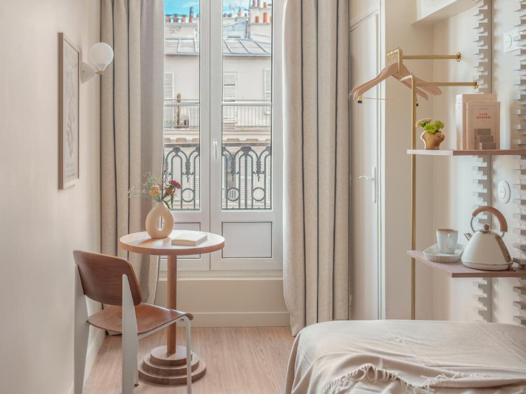 巴黎巴斯酒店的客房设有床、桌子和窗户。