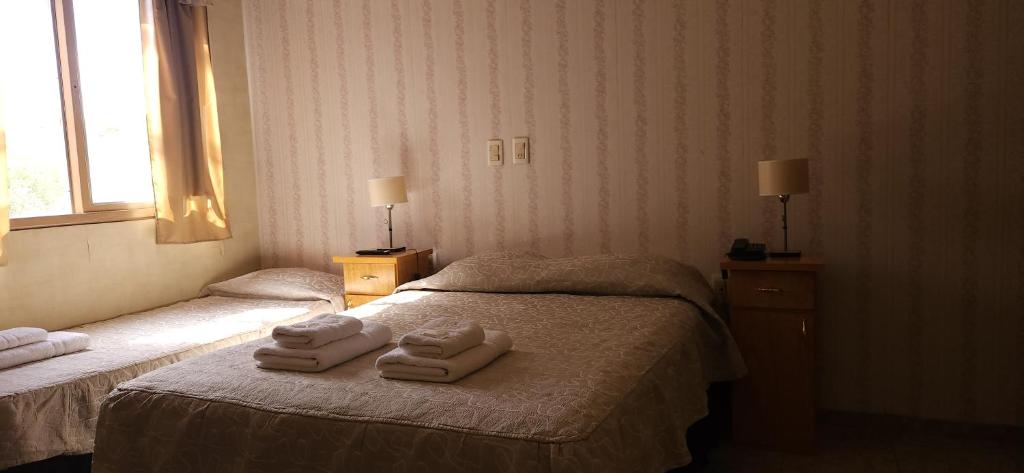 门多萨Hotel Geminis的酒店客房的床上配有2条毛巾