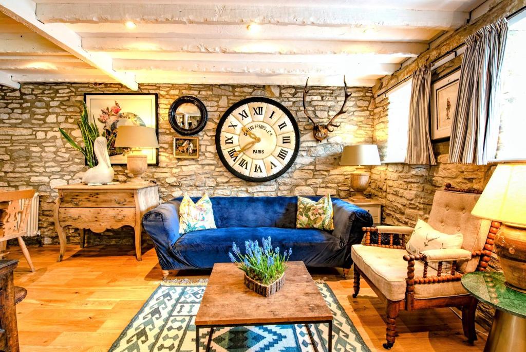 斯沃尼奇Cosy Little Hyde Cottage, Swanage的客厅配有蓝色的沙发和墙上的时钟