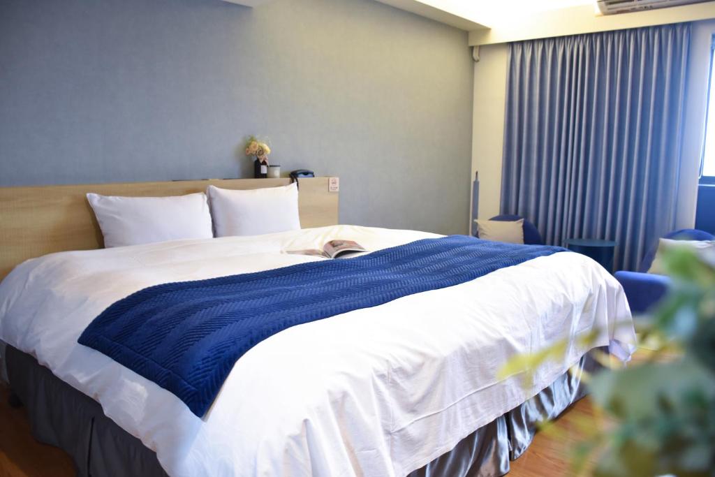 台中市塔木德酒店Choice 台中公园馆的床上有蓝色和白色的毯子