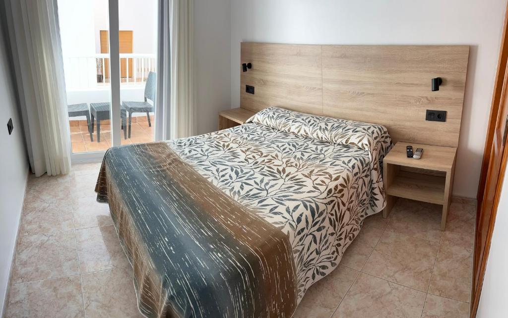 卡沃内拉斯胡安卡洛斯旅馆的一间卧室配有一张带木制床头板的床