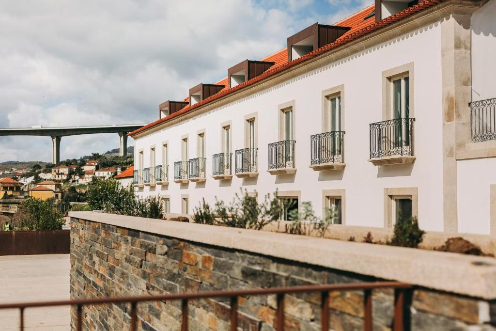 比索达雷加Torel Quinta da Vacaria - Douro Valley的一座带窗户的白色建筑,后方有一座桥