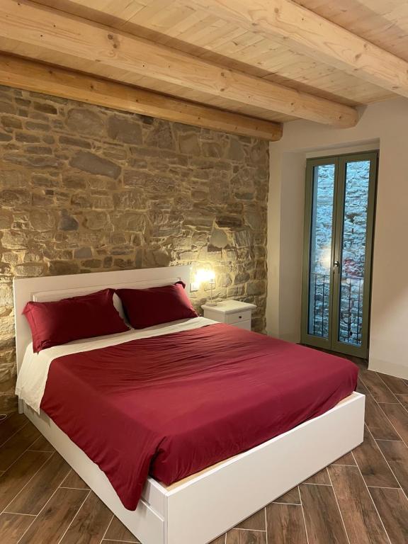 RoccaveranoAlbergo del Bramante的一间卧室配有一张红色的床和石墙