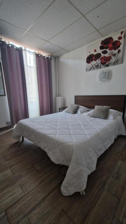 戛纳北部旅馆的卧室配有一张带白色棉被的大床