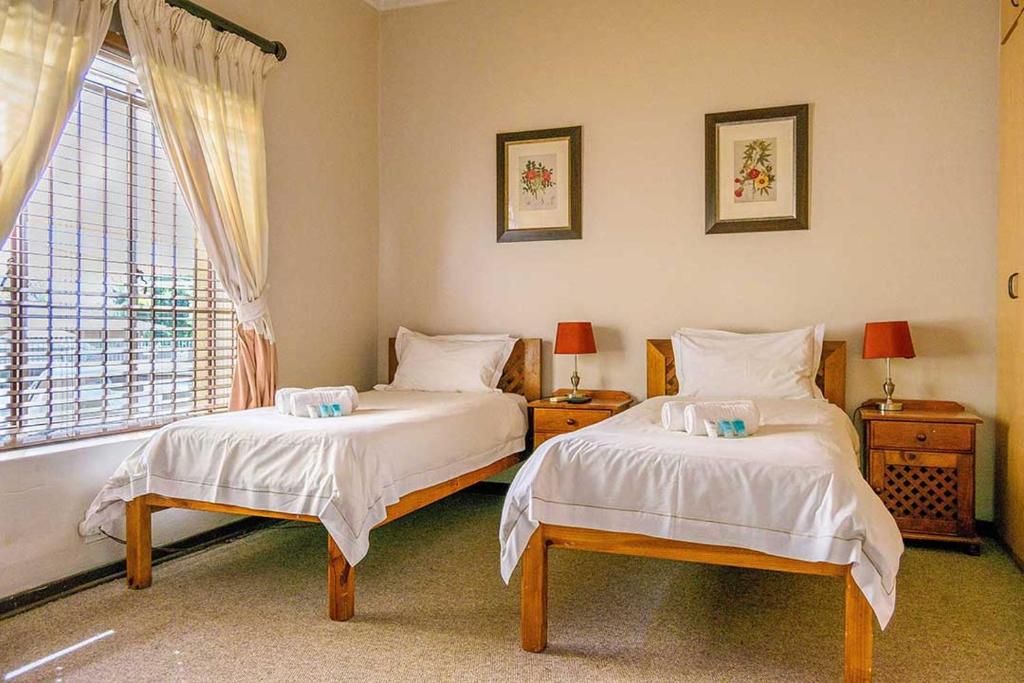 比勒陀利亚RIETONDALE LODGE的一间卧室设有两张床和窗户。