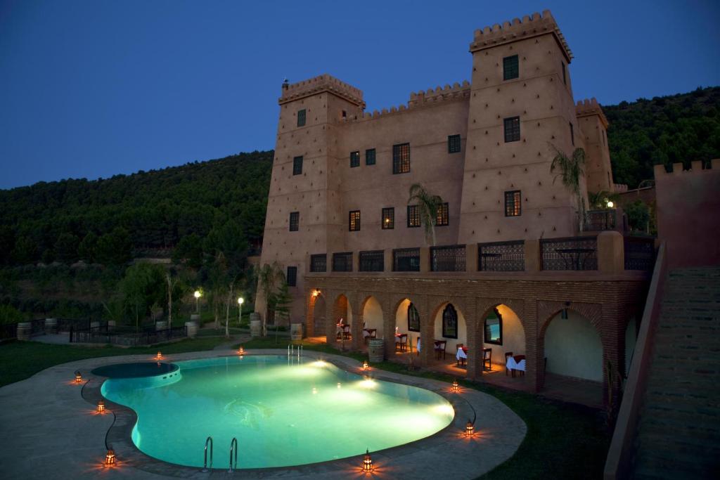 代姆纳特伊利古堡酒店的一座大型建筑,前面设有一个游泳池
