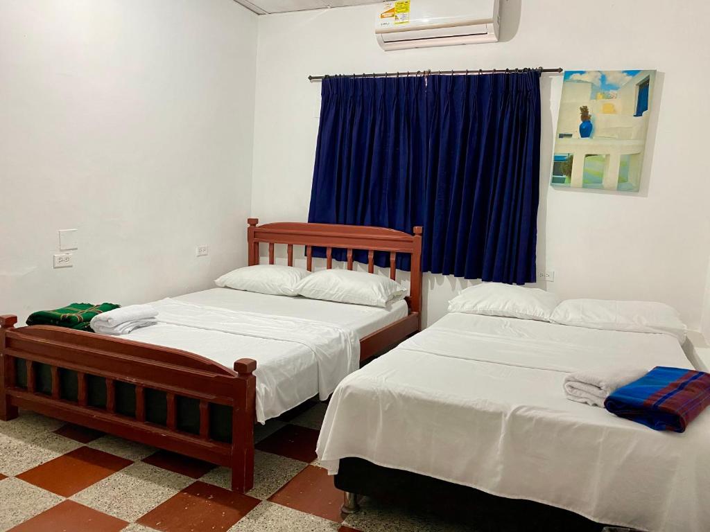 卡塔赫纳Habitación Multiple cerca de aeropuerto的一间卧室配有两张床和蓝色窗帘