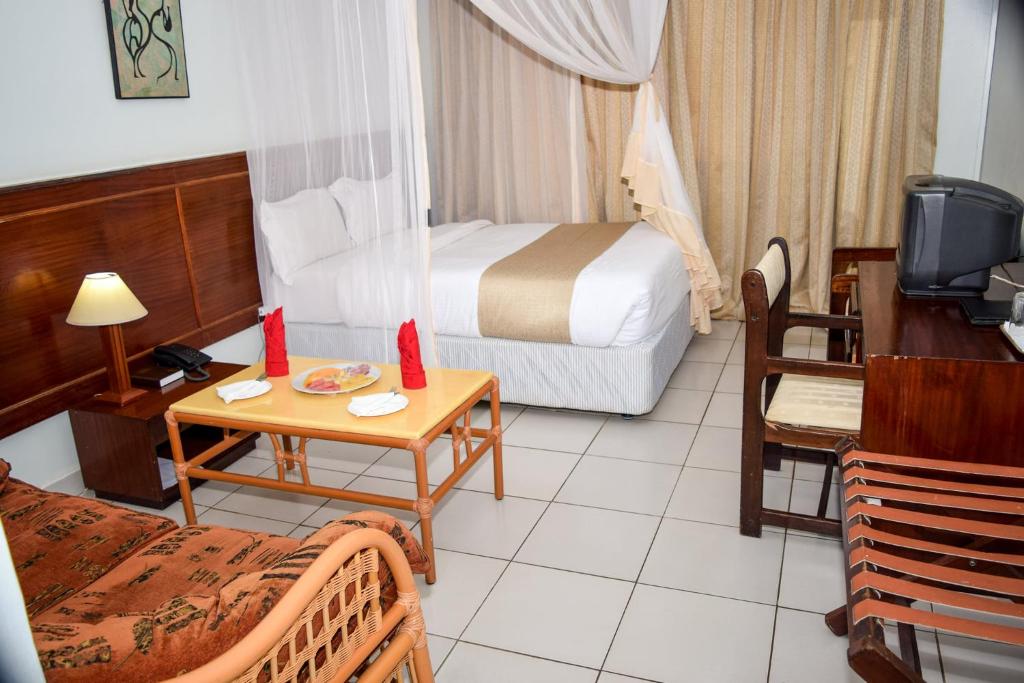 马查科斯Garden Hotel Machakos的酒店客房设有一间带一张床和一张书桌的卧室