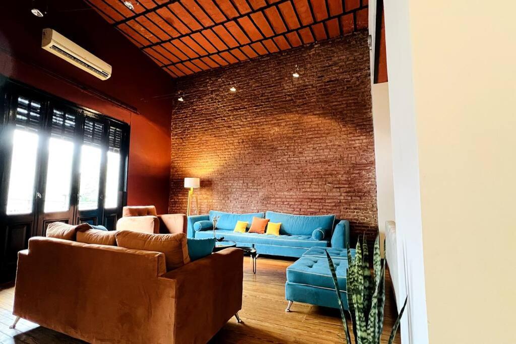 布宜诺斯艾利斯Casa grande en Palermo Soho的客厅设有蓝色的沙发和砖墙
