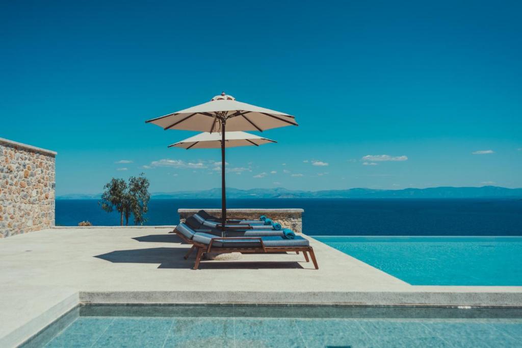 利昂尼迪翁Sampatiki Suites - 4 Star Seaview Luxury Suites With Breakfast And Spa - Opened 2024的一组躺椅,在游泳池畔配有遮阳伞