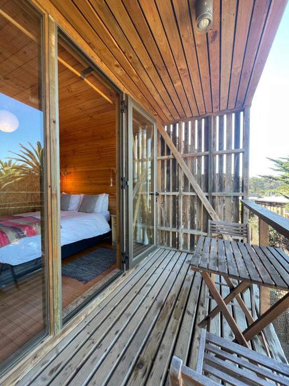 康康La Ritoqueña Hotel de Playa的木制门廊,甲板上设有床和长凳