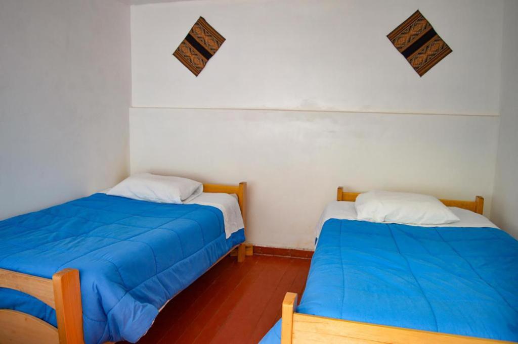 库斯科Fun Packers Hostel的小客房内的两张床,配有蓝色的床单