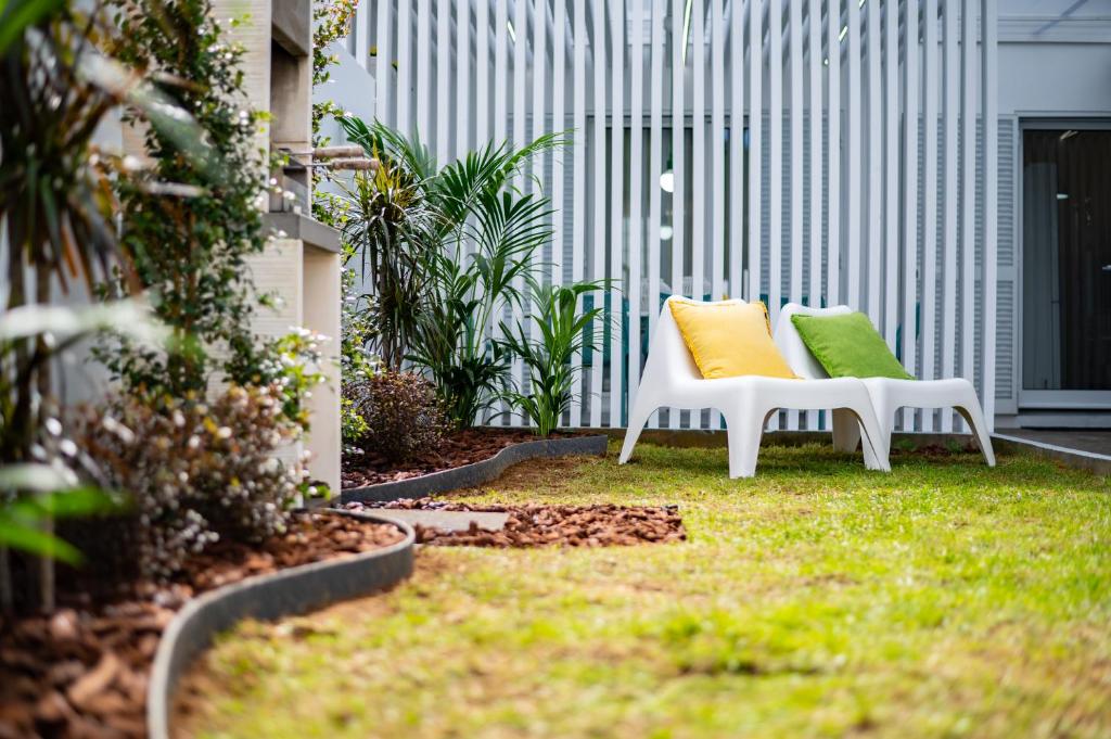 蓬塔德尔加达Casa Cecilia Meireles的两把白色椅子和五颜六色的枕头在院子里