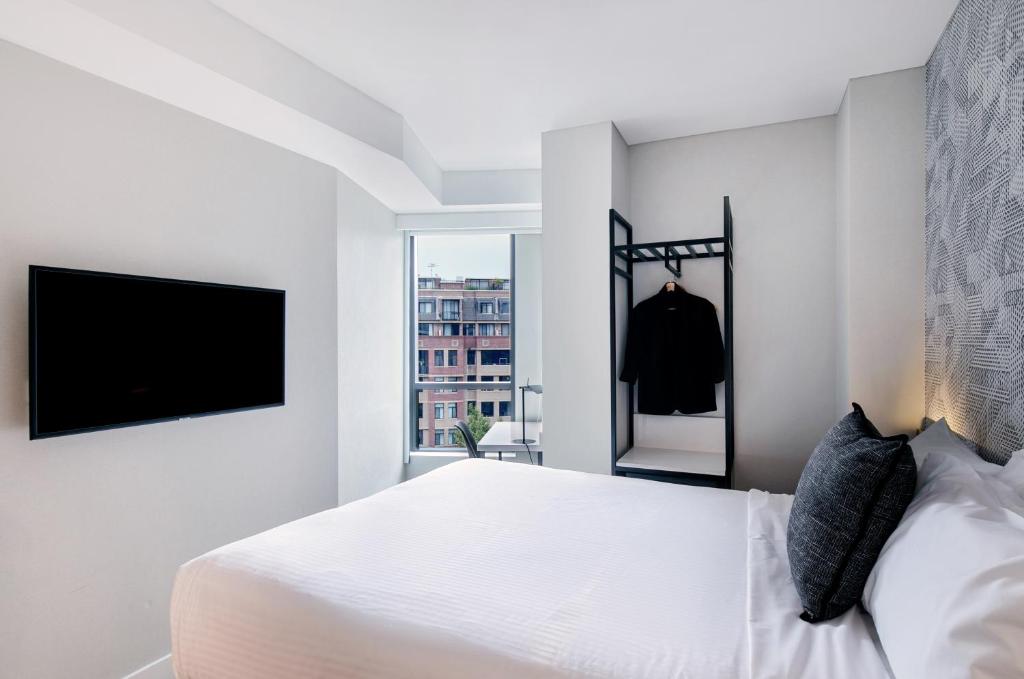 悉尼Kith Hotel Darling Harbour的一间白色卧室,配有床和电视
