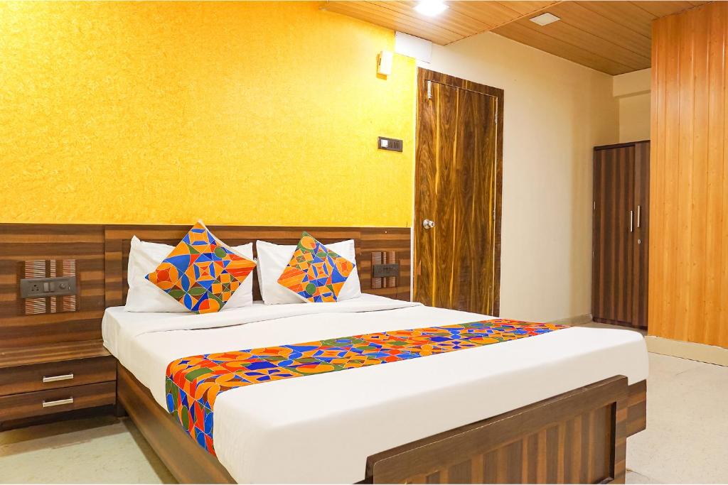 浦那FabExpress Gargi Executive的一间卧室配有一张带色彩缤纷枕头的大床
