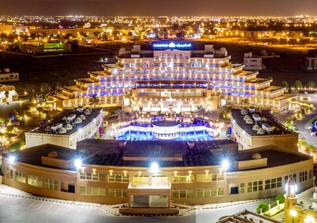 阿尔布亚米Al Salam Grand Hotel & Resort的夜晚大建筑的空中景观