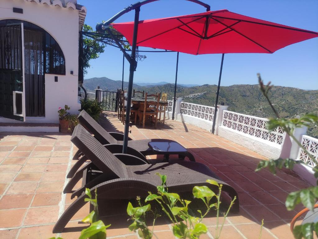 孔佩塔Venta Real 12v的一个带红色遮阳伞和椅子及桌子的庭院
