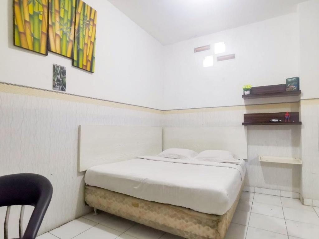 雅加达Kartini Residence RedPartner的一间卧室配有一张床和一把椅子