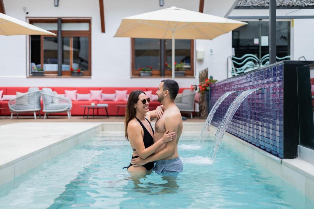 卡里拉Neptuno Hotel & SPA 4 Sup的站在游泳池中的男女