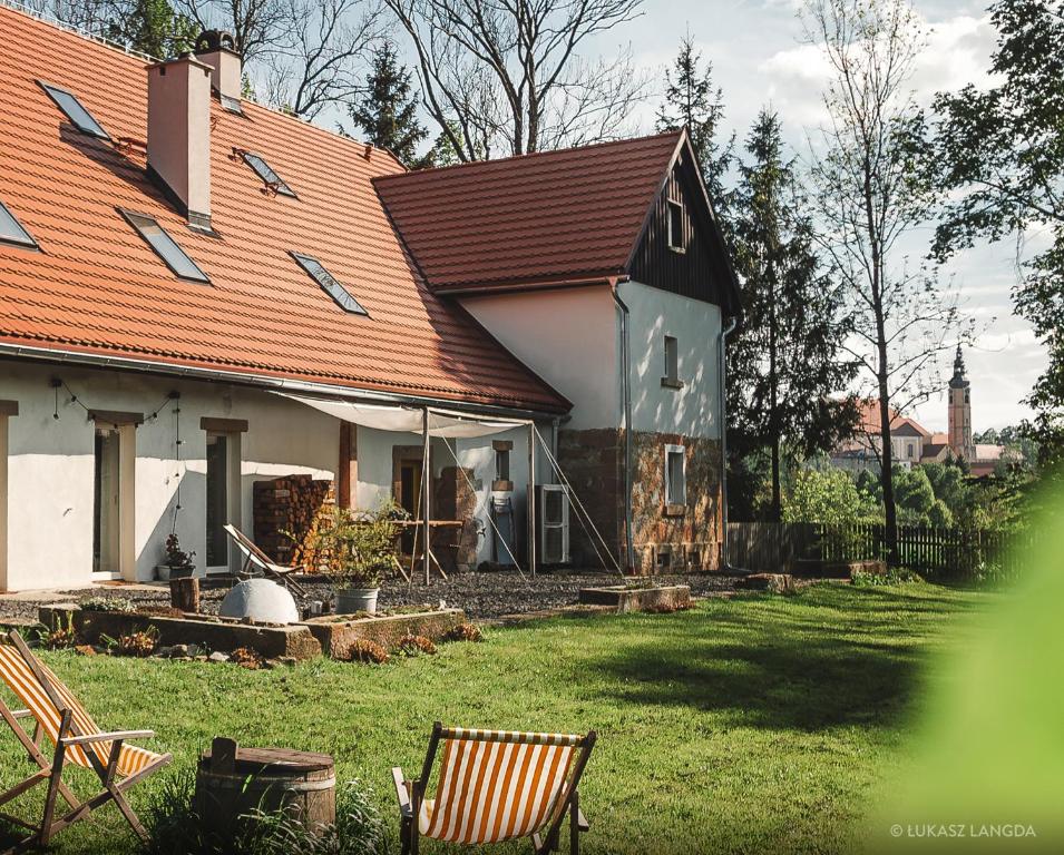 LubomierzWietorówka的一座红色屋顶的房子和一个带椅子的庭院