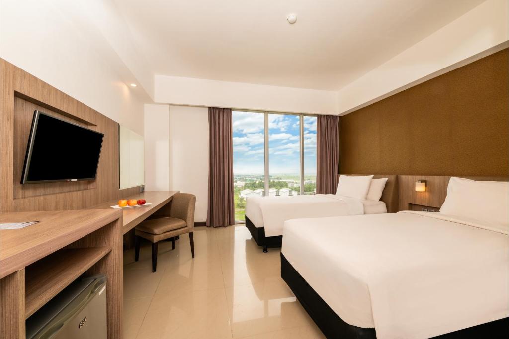 班贾尔马辛ASTON Banua Banjarmasin Hotel & Convention Center的酒店客房设有两张床和电视。