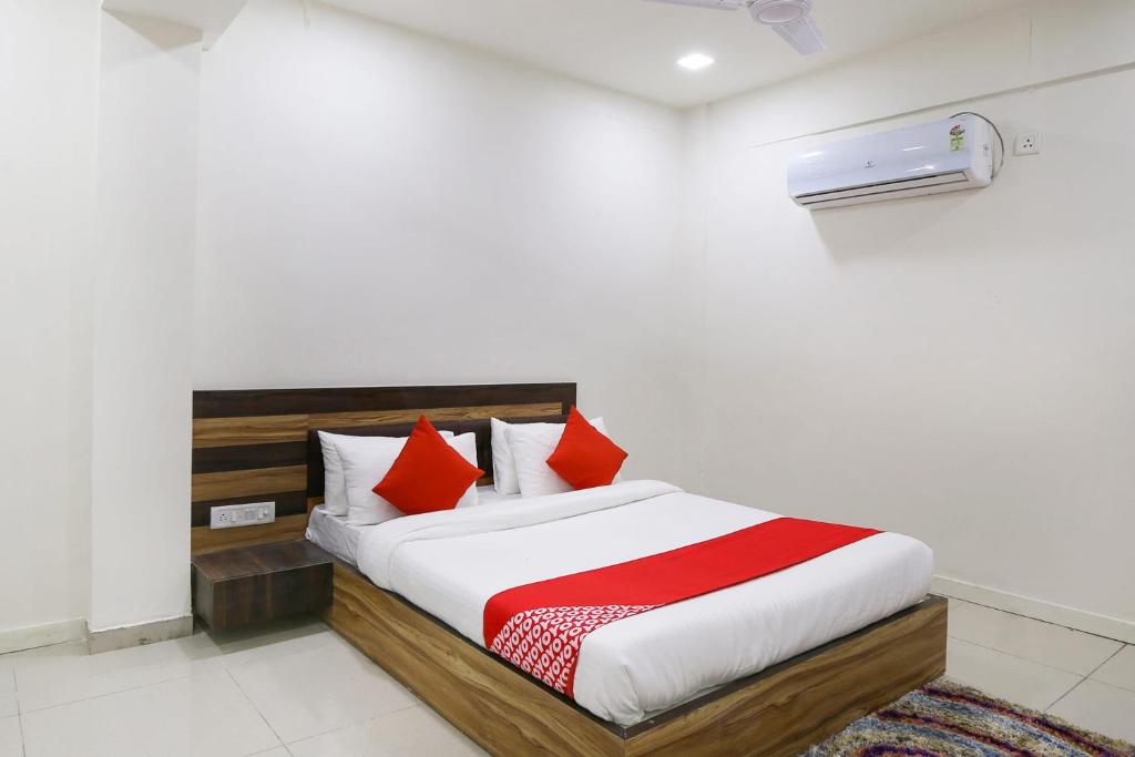 巴罗达OYO Hotel Shiv Kunj的一间卧室配有红色和白色枕头的床