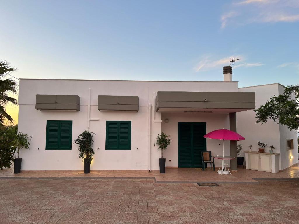滨海波利尼亚诺Fusella Country House/Villa a Polignano Vista Mare的前面有粉红色伞的白色建筑