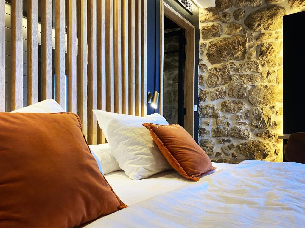 比利亚霍约萨Pou by Seaward Suites Only Adults的一张带两个枕头的床,旁边是石墙